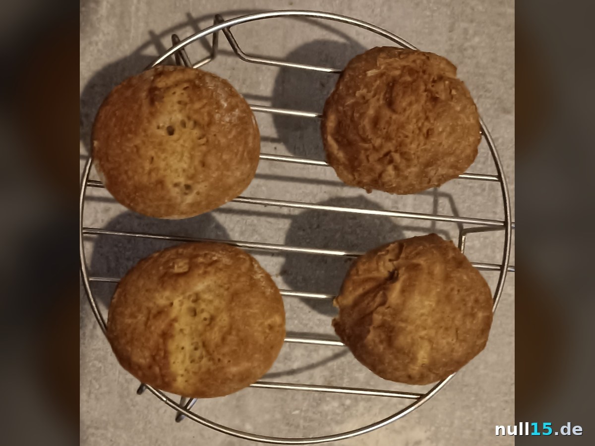 Vier goldbraune Low-Carb-Brötchen aus der Heißluftfritteuse auf einem Gitter