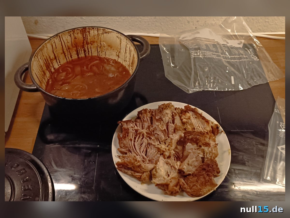 Fertiges, auseinandergezupftes Pulled Pork vom Schweinenacken mit Zwiebel-Soße im Topf